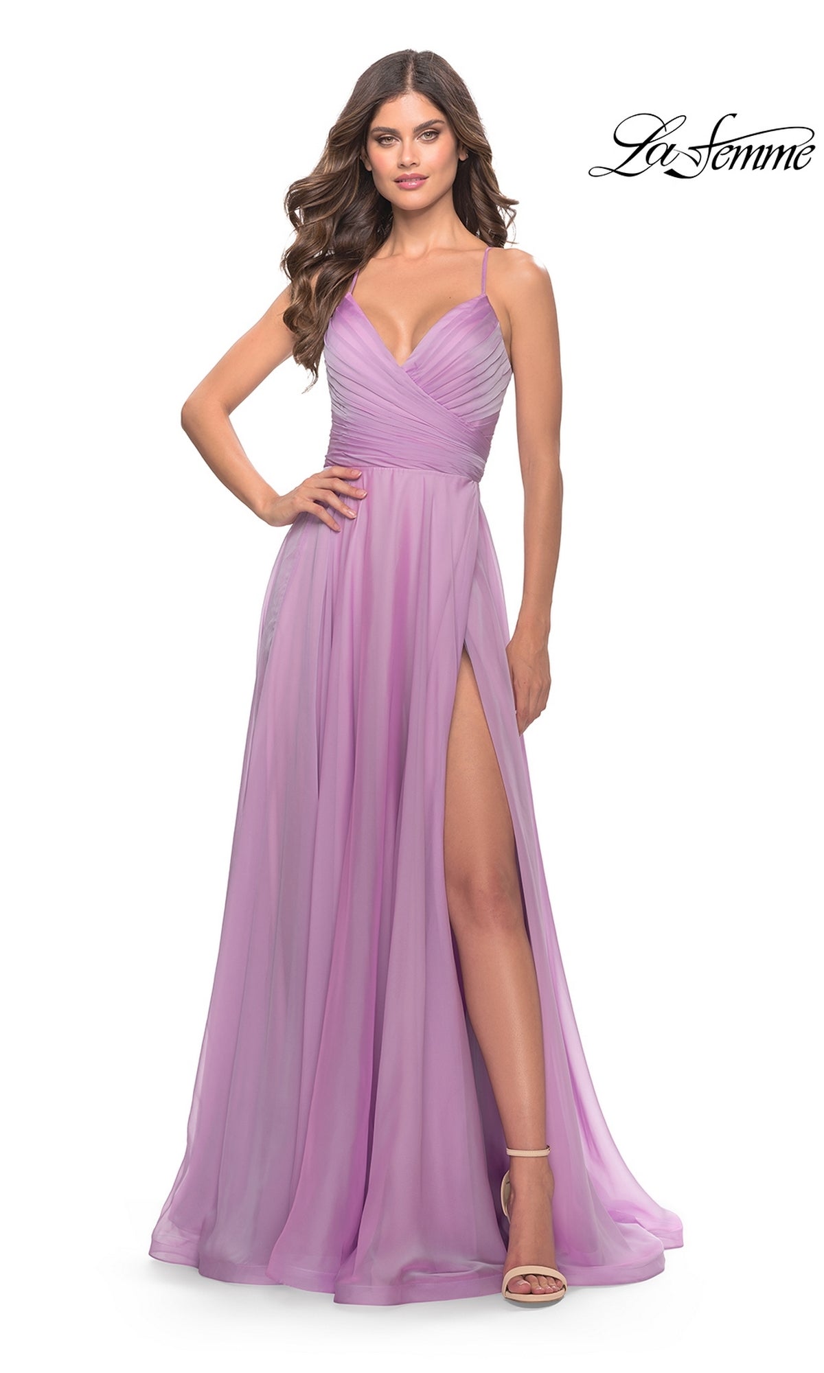 A woman in a lavender La Femme V-Neck Long Tulle Prom Ball Gown 30840 with spaghetti straps, a ruched bodice, and a high slit stands against a plain white background.